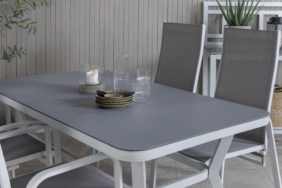 Rechteckiger Esstisch mit grauem Gestell und schwarzer Mattglas-Tischplatte, daneben zwei graue Relaxsessel aus Textilene mit Aluminiumbeinen.