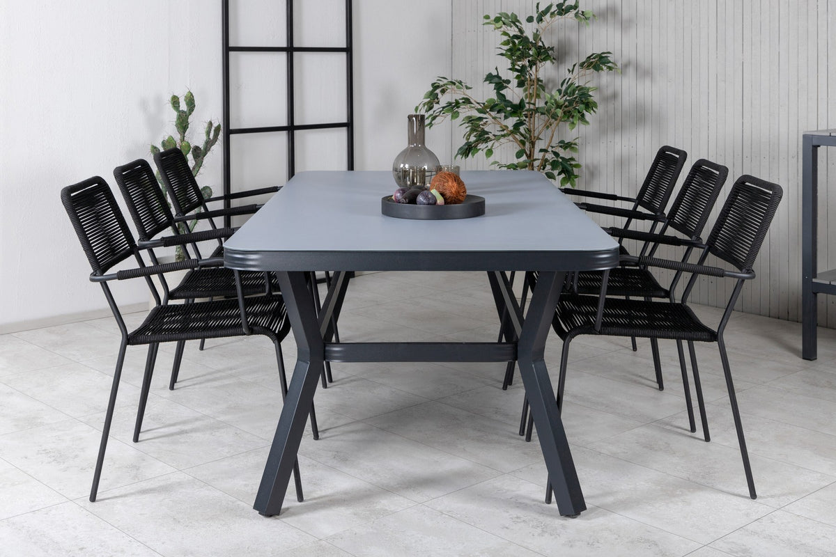 Rechteckiger Esstisch mit schwarzer Glasplatte und Stahlbeinen, daneben zwei schwarze Stühle mit Textilene-Bezug, Gartenmöbel-Set von Venture Home.