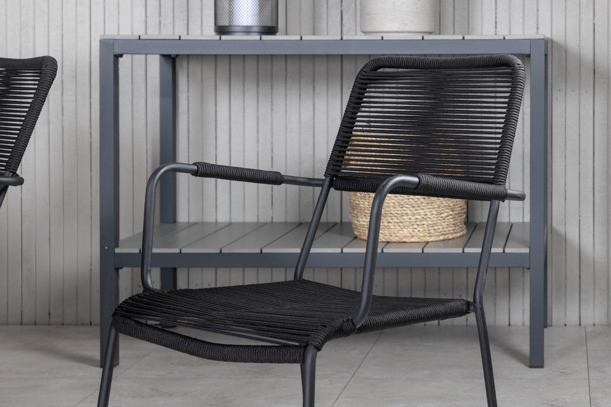 Rechteckiger Esstisch mit schwarzer Glasplatte und Stahlbeinen, daneben zwei schwarze Stühle mit Textilene-Bezug, Gartenmöbel-Set von Venture Home.