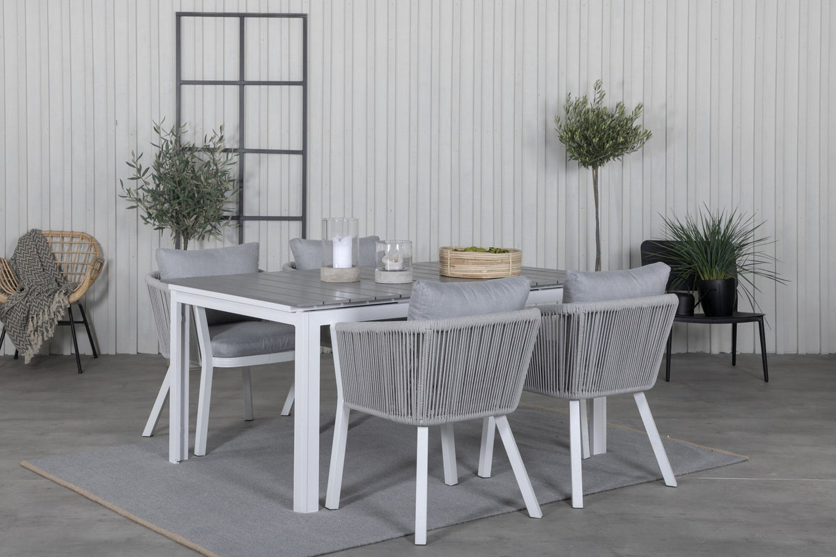 Zwei graue Esszimmerstühle mit Seil-Bezug und Aluminiumgestell neben einem weissen, ausziehbaren Aintwood-Esstisch im Garten.