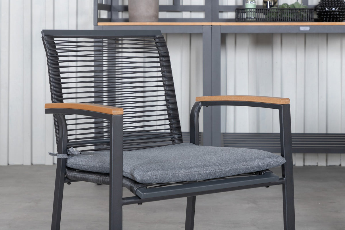 Zwei schwarze Aluminium-Stühle mit Polyester-Bezug und ein rechteckiger, ausziehbarer Teak-Tisch mit schwarzer Tischplatte.