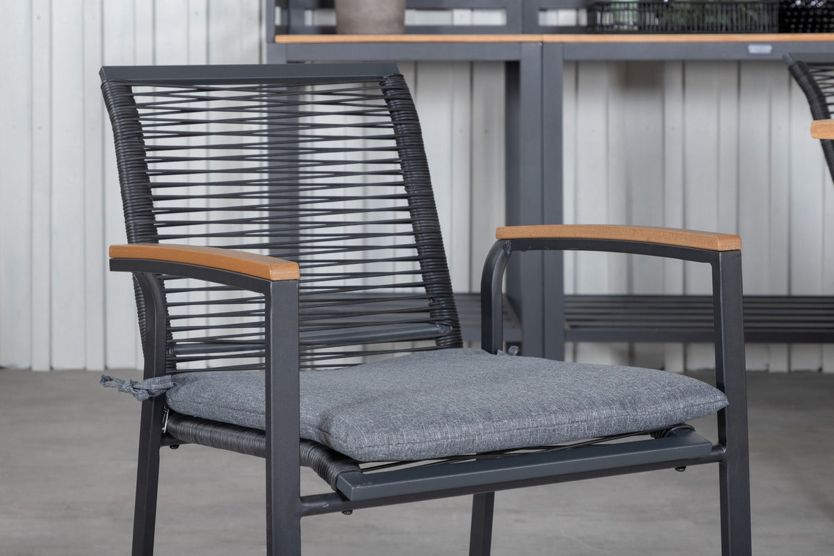 Zwei schwarze Aluminium-Stühle mit Polyester-Bezug und ein rechteckiger, ausziehbarer Teak-Tisch mit schwarzer Tischplatte.