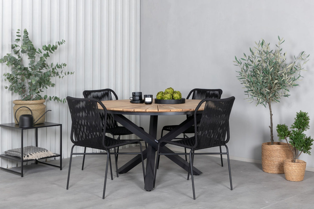 Vier schwarze Esszimmerstühle mit Aluminiumgestell und Polyesterbezug neben rundem Teak-Esstisch mit Stahlbeinen, Durchmesser 140 cm.