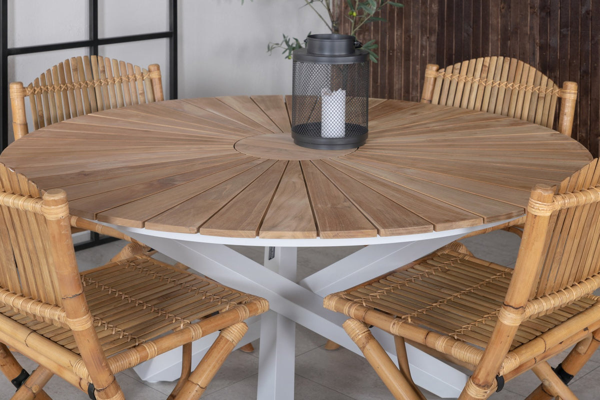 Runder Esstisch ⌀140 aus Teakholz mit Rattanbeinen neben Caféstuhl mit Aluminiumgestell und Bezug aus Baumwolle und Polyester in Naturfarbe.