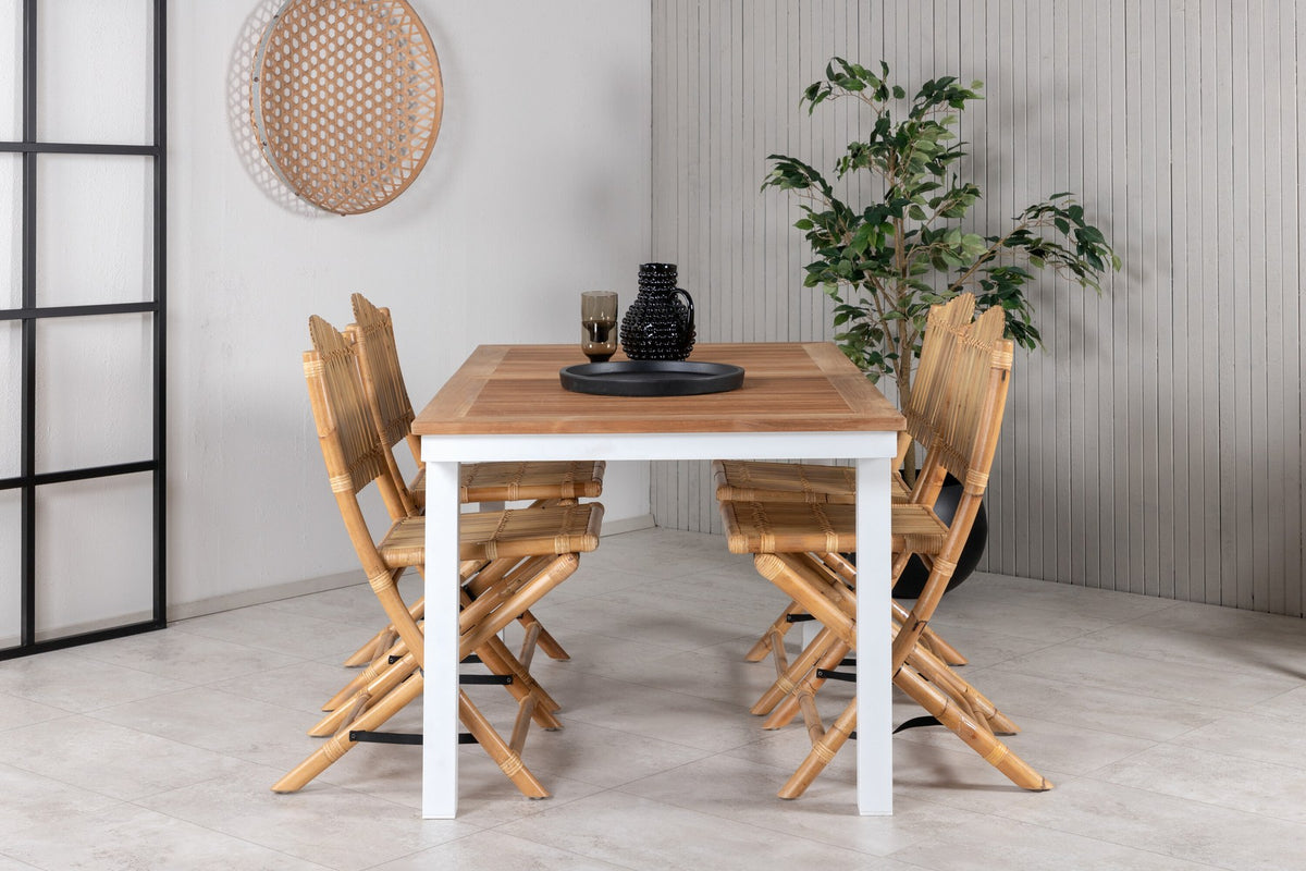 Foto zeigt einen Cafe Stuhl mit Rattan-Beinen und Stoffbezug in Natur sowie einen rechteckigen Teakholz-Esstisch mit weissem Aluminiumgestell.