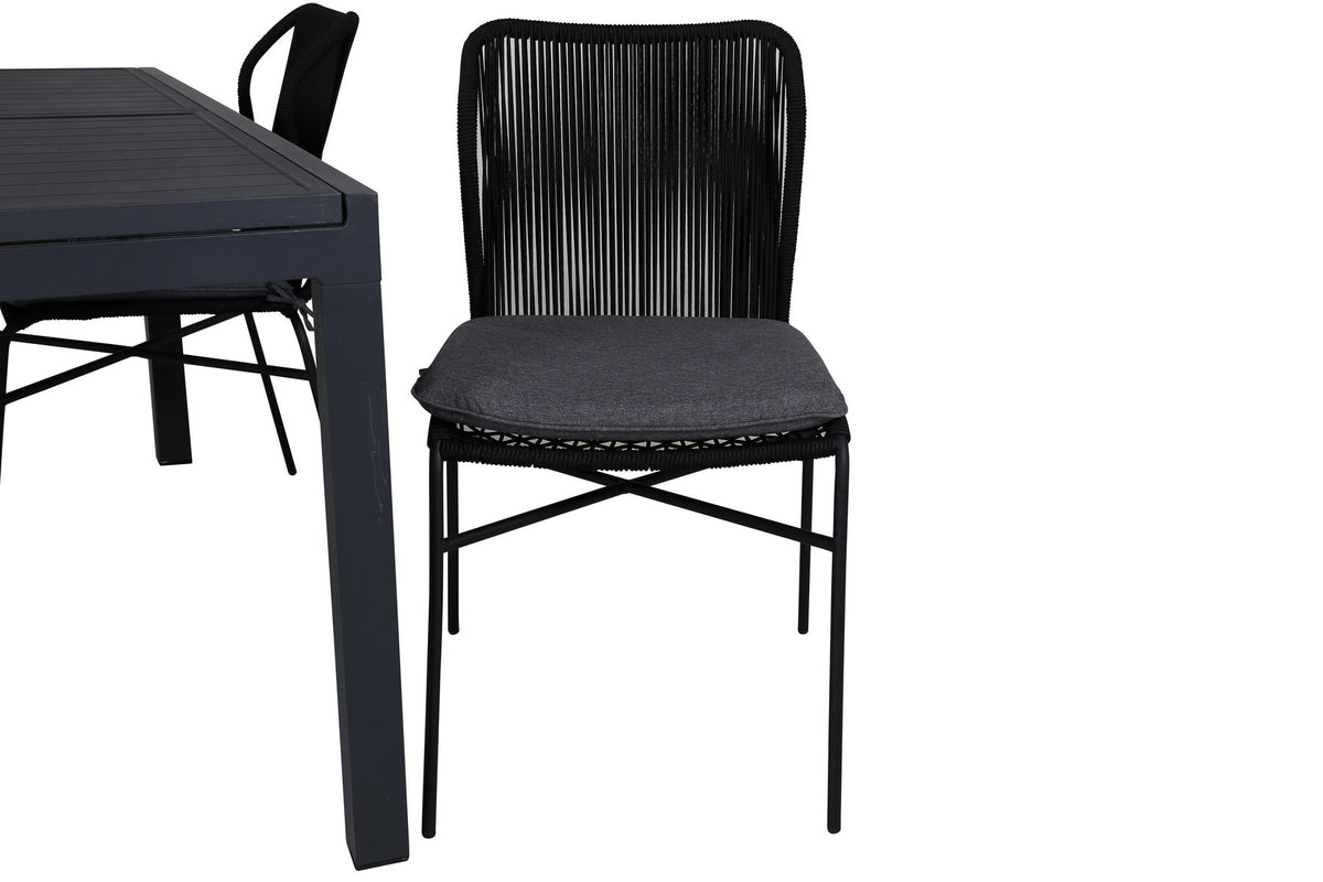 Vier schwarze Esszimmerstühle mit Polyesterbezug und pulverbeschichtetem Aluminiumgestell neben einem rechteckigen Esstisch aus schwarzem Aluminium.