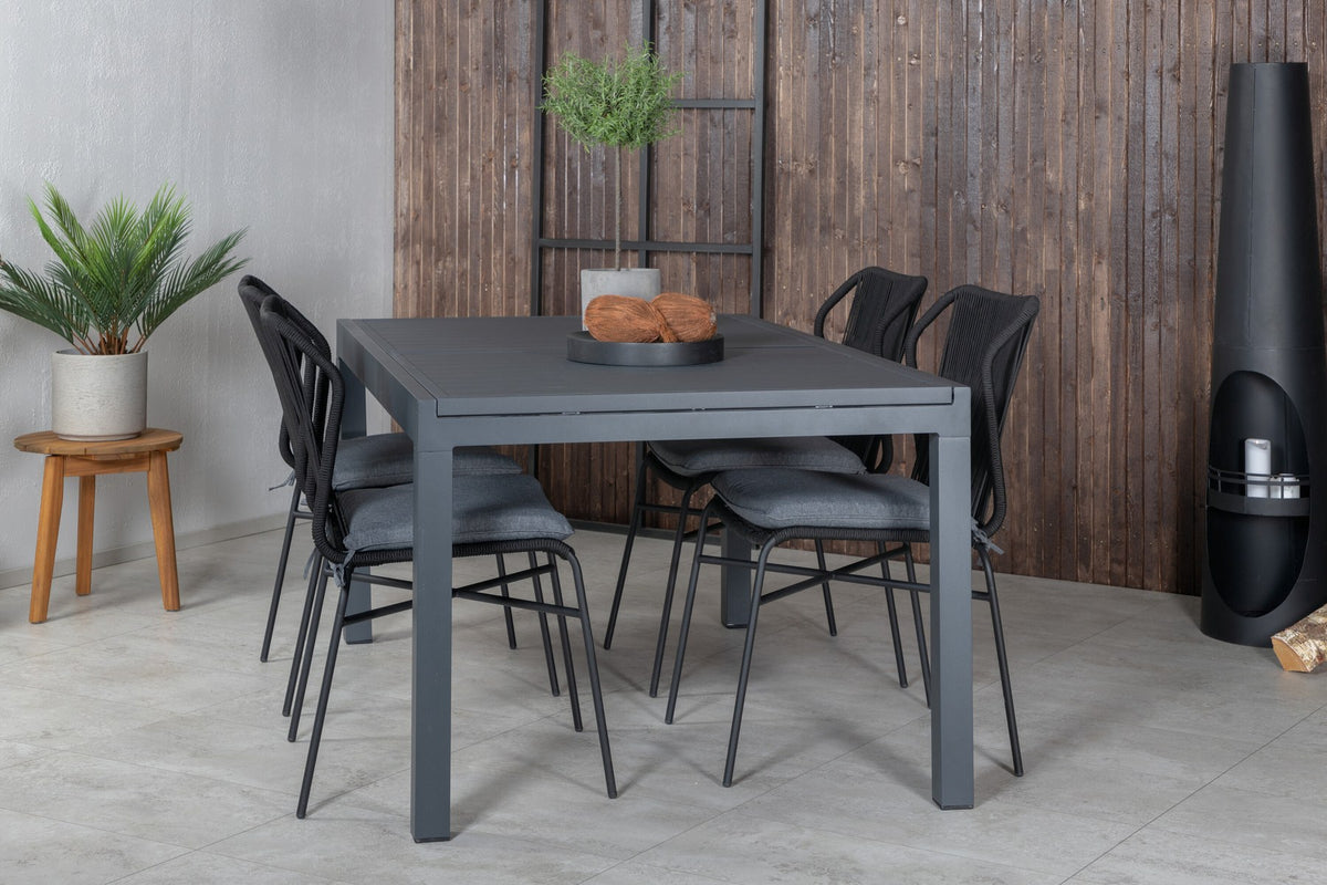Vier schwarze Esszimmerstühle mit Polyesterbezug und pulverbeschichtetem Aluminiumgestell neben einem rechteckigen Esstisch aus schwarzem Aluminium.