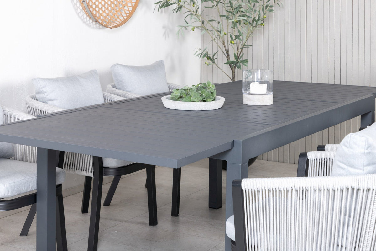 Gartentischset aus Aluminium: ausziehbarer Marbella Tisch mit schwarzem Gestell und 4 Virya Stühlen mit grauem Kissen im Aussenbereich.