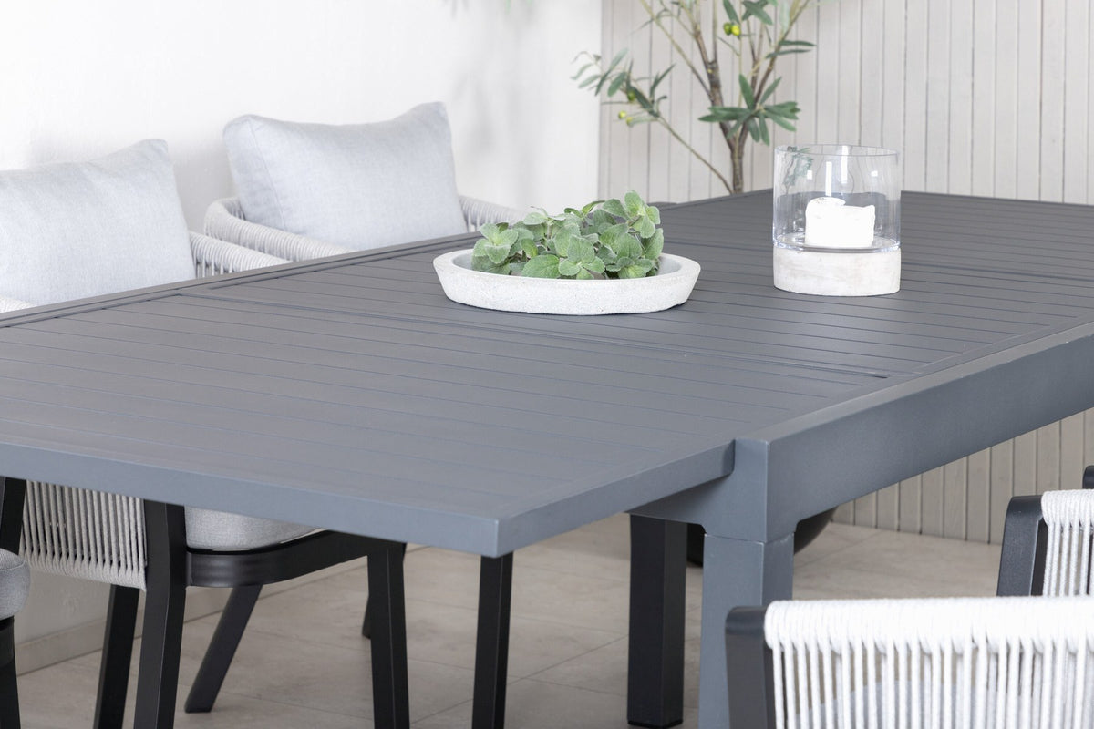 Gartentischset aus Aluminium: ausziehbarer Marbella Tisch mit schwarzem Gestell und 4 Virya Stühlen mit grauem Kissen im Aussenbereich.