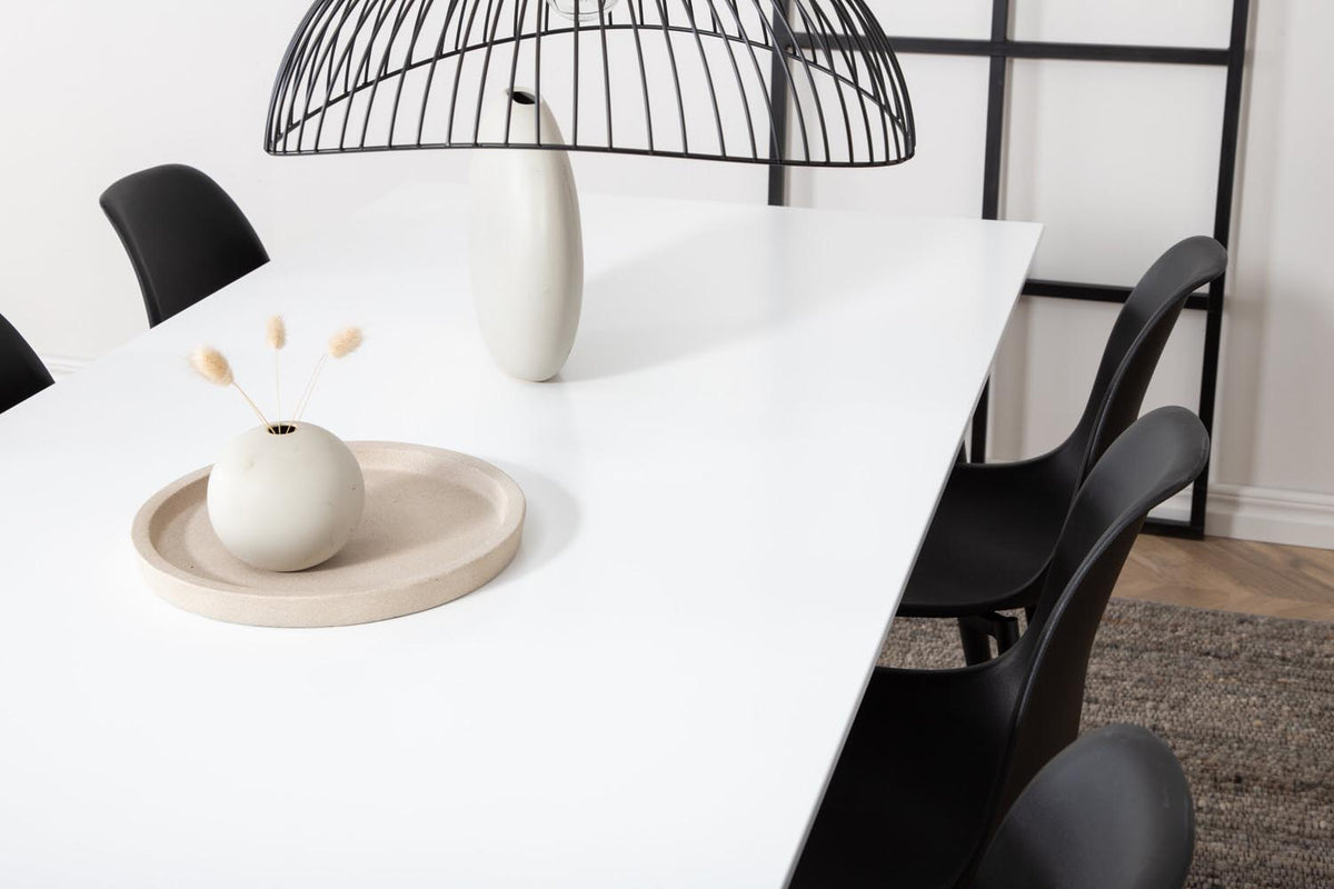 Esszimmerset Jimmy mit ausziehbarem Tisch aus weissem HPL und MDF, schwarzen Stahlbeinen sowie sechs schwarzen Polar-Stühlen mit Kunststoffsitz.