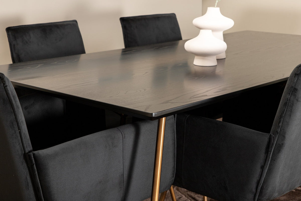 Petra Esszimmerset: Esstisch mit schwarzer MDF-Platte und Furnier in Used-Optik, sechs Stühle mit Samtbezug in Kupfer/Schwarz und Eisenbeinen.