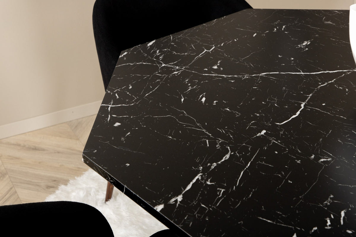 Zwei schwarze Esszimmerstühle mit Nussbaum-Beinen und Polyester-Sitzfläche neben rundem Esstisch Ø110cm mit schwarzer MDF-Platte und Stahlbeinen.