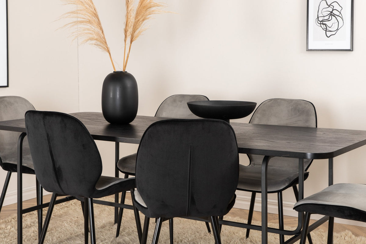 Zwei graue Esszimmerstühle mit Samtbezug und Eisenbeinen neben einem rechteckigen schwarzen Esstisch aus MDF mit Furnier und Metallgestell.