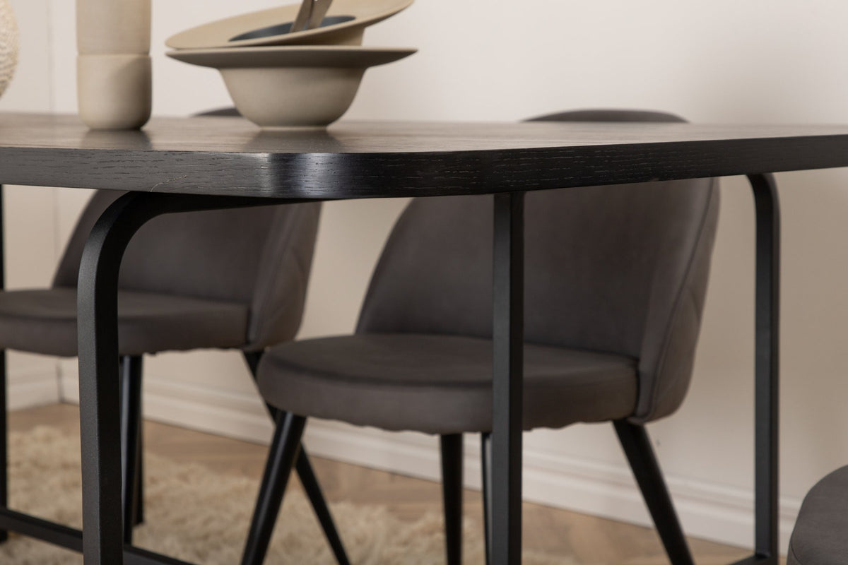 Esszimmerset Uno & Velvet: rechteckiger Esstisch mit schwarzer MDF-Furnier-Platte und Metallgestell, dazu Stühle mit grauem Samtbezug und Eisenbeinen.