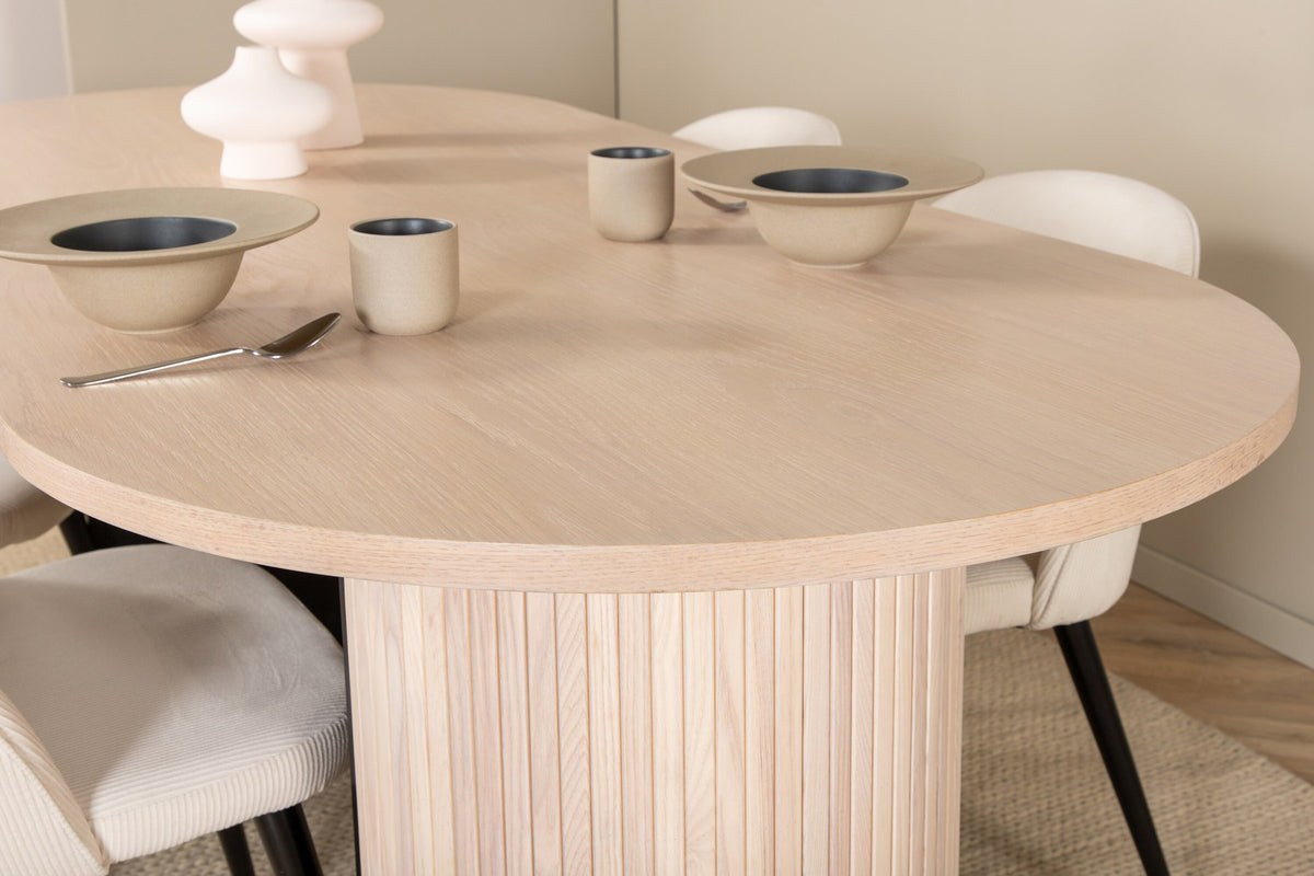 Ovaler Esstisch mit weiss lasierter MDF-Tischplatte und vier Samtstühlen mit schwarzen Stahlbeinen, cremefarbenes Esszimmerset.