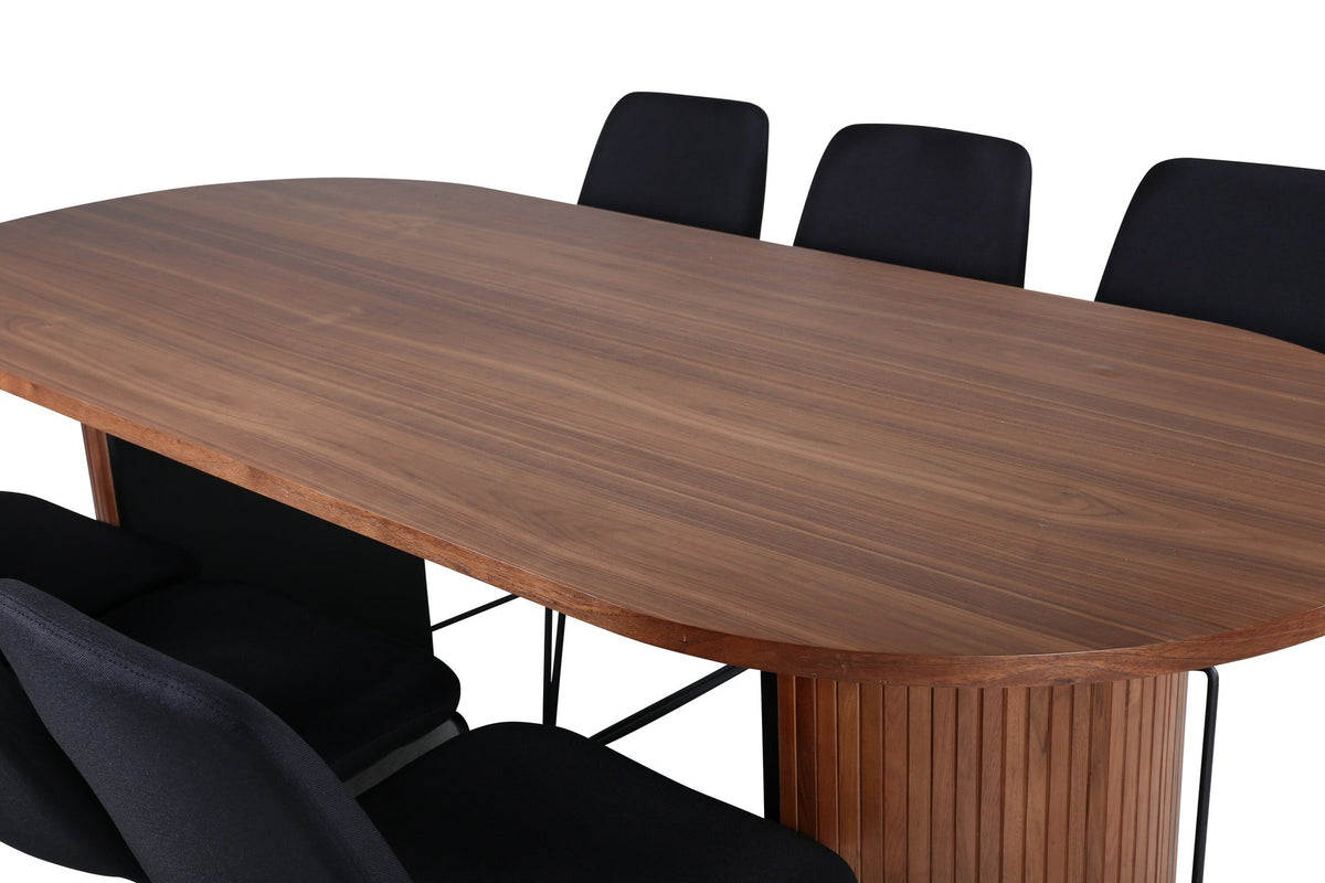 Ovaler Esstisch mit Nussbaum-Furnier und MDF-Platte, kombiniert mit zwei schwarzen Esszimmerstühlen mit Polyesterbezug und schmalen Stahlbeinen.