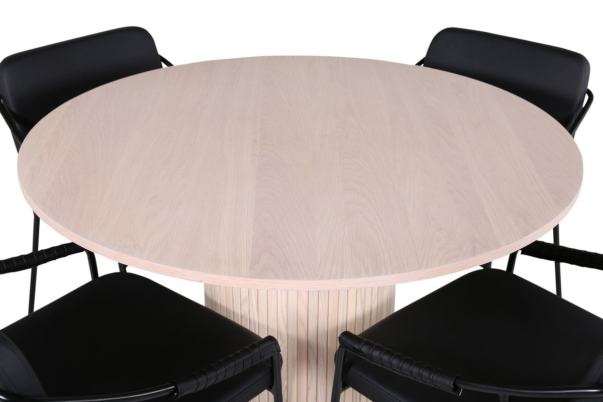 Rundes Esszimmerset aus MDF: Tischplatte Ø110 cm in Whitewash mit gerippten Beinen, dazu zwei schwarze Stühle mit Eisenbeinen.