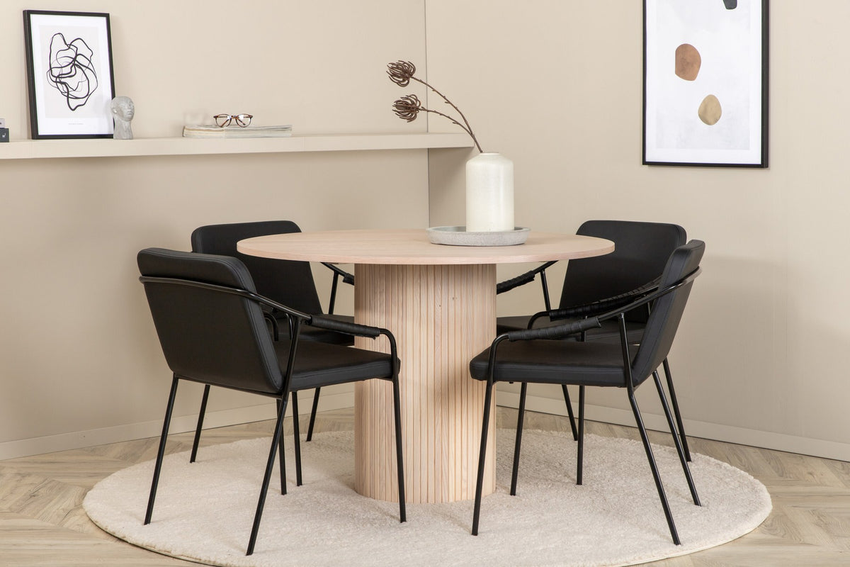 Rundes Esszimmerset aus MDF: Tischplatte Ø110 cm in Whitewash mit gerippten Beinen, dazu zwei schwarze Stühle mit Eisenbeinen.