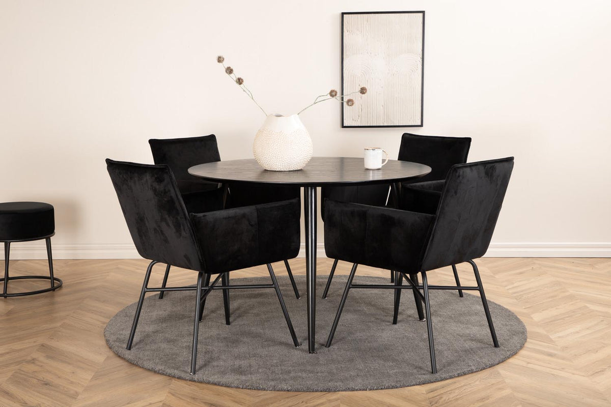 Rundes Esszimmerset Dipp mit schwarzer MDF-Tischplatte, Ø115 cm, und vier Petra-Stühlen mit schwarzem Samtsitz und Eisenbeinen.