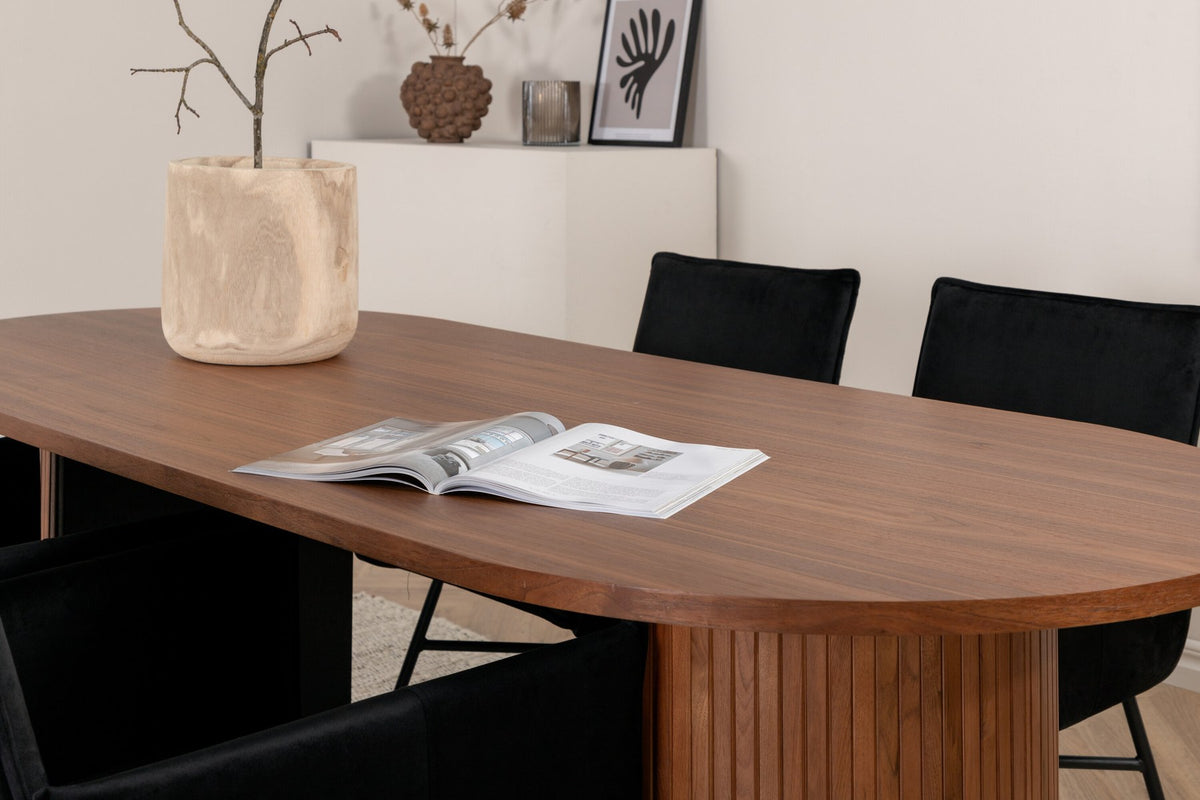 Ovaler Esstisch aus MDF mit Nussbaum-Furnier, 200x90 cm, kombiniert mit vier schwarzen Esszimmerstühlen mit pulverbeschichteter Oberfläche.