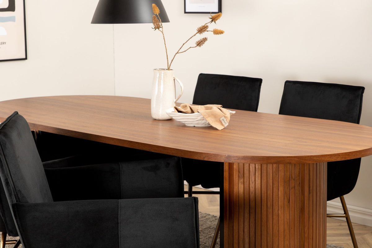 Ovaler Esstisch aus MDF mit Nussbaum-Furnier, 200x90 cm, kombiniert mit vier schwarzen Esszimmerstühlen mit pulverbeschichteter Oberfläche.