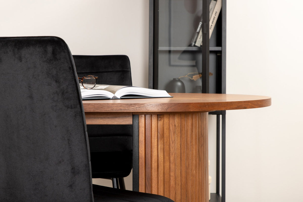 Ovaler Esstisch mit Nussbaum-Tischplatte aus MDF und Furnier sowie zwei schwarze Esszimmerstühle mit Samtsitz und schmalen Beinen.