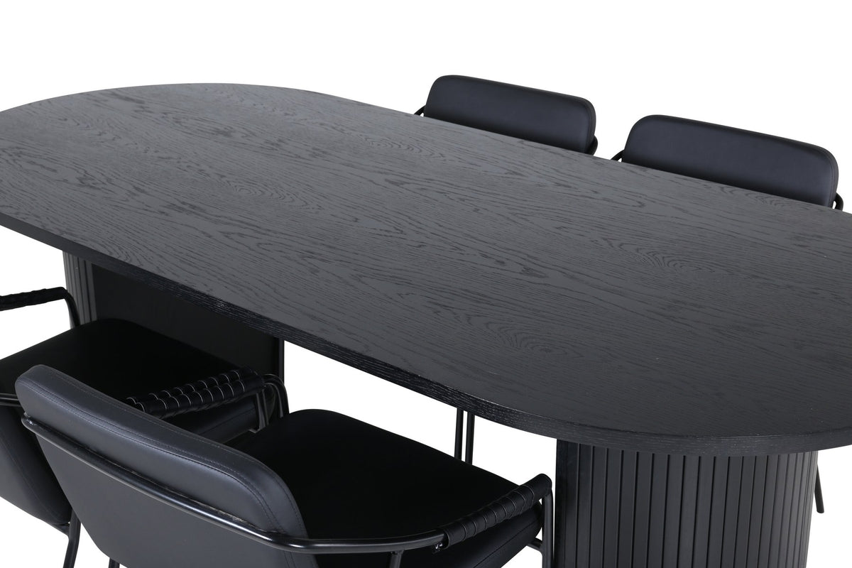 Zwei schwarze Esszimmerstühle mit Beinen aus Eisen und Sitzfläche aus Polyurethan-Membran neben ovalem MDF-Esstisch in Schwarz.
