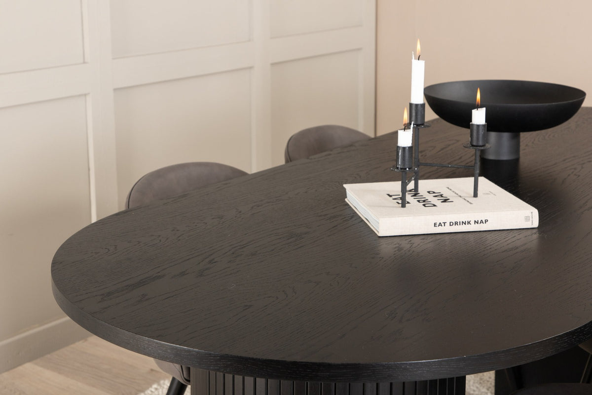 Ovaler Esstisch aus MDF mit schwarzer Furnier-Tischplatte und zwei Esszimmerstühlen mit grauem Mikrofaser-Sitz und Eisenbeinen.