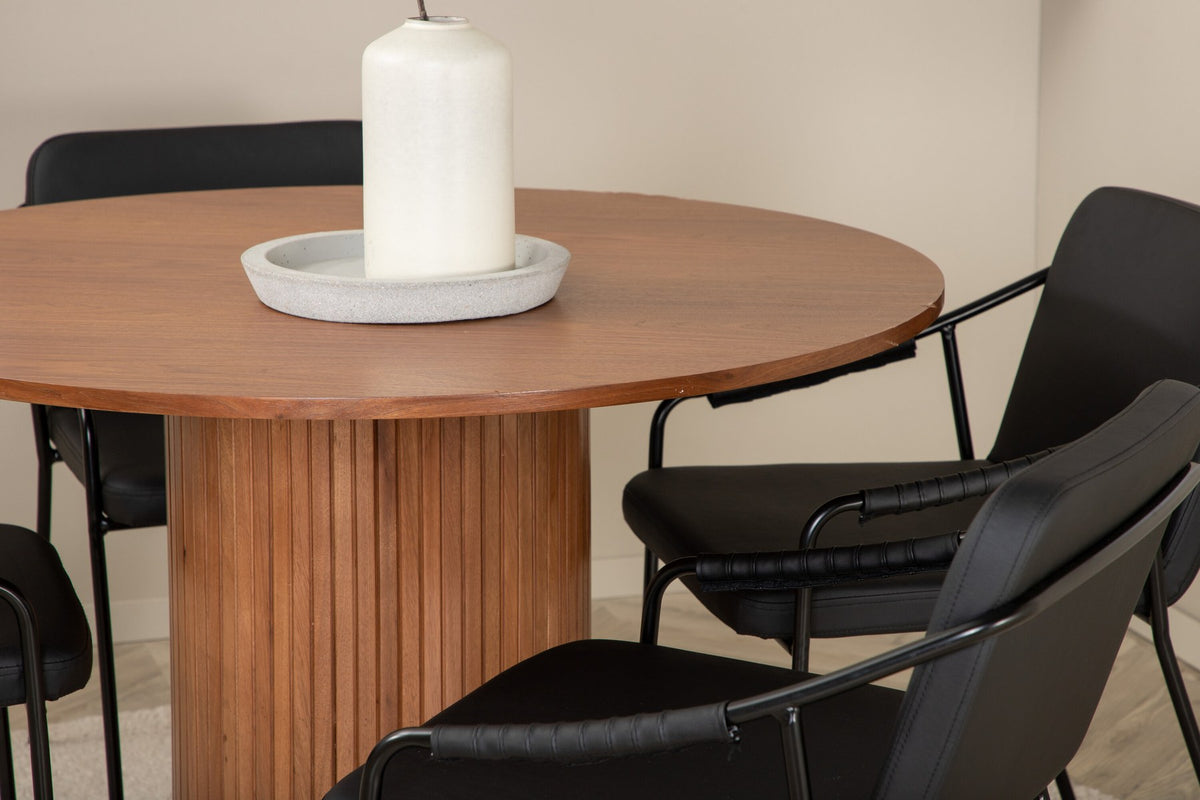 Rundes Esszimmerset mit Tisch aus MDF in Nussbaum-Optik ⌀110 cm und zwei schwarzen Stühlen mit Pulverbeschichtung und Eisenbeinen.