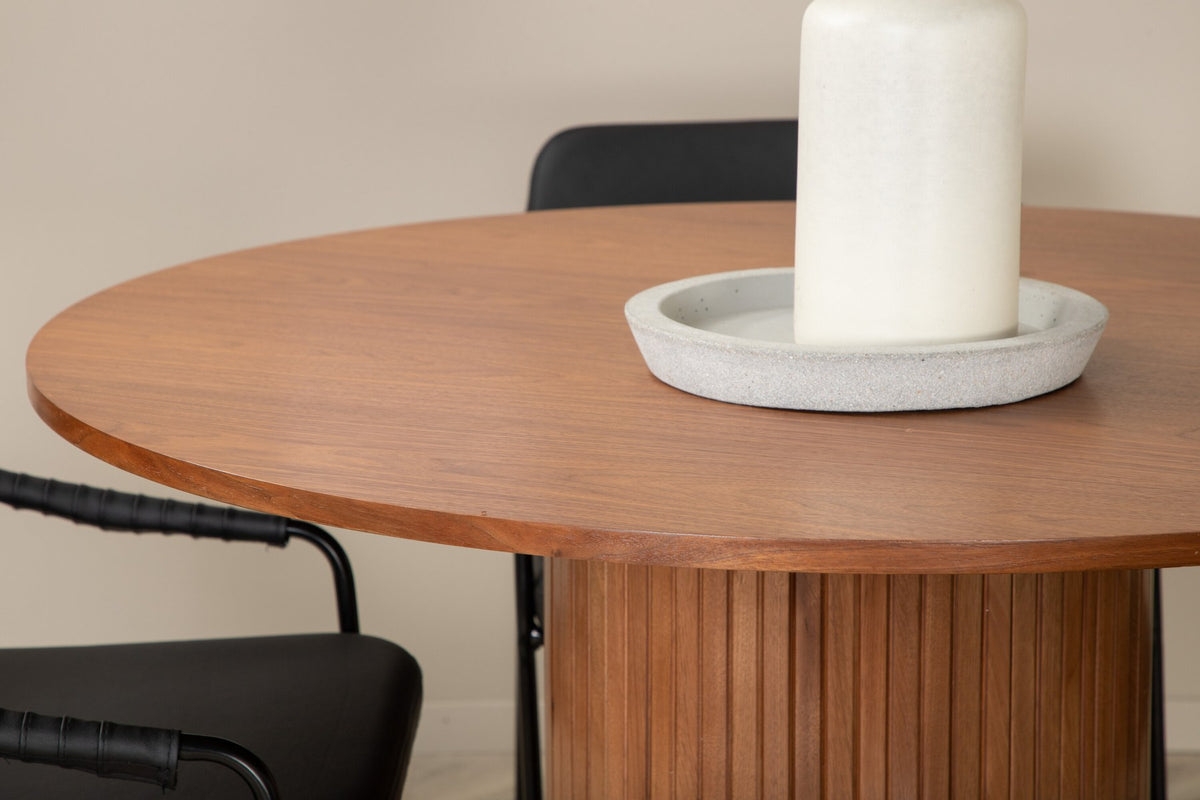 Rundes Esszimmerset mit Tisch aus MDF in Nussbaum-Optik ⌀110 cm und zwei schwarzen Stühlen mit Pulverbeschichtung und Eisenbeinen.