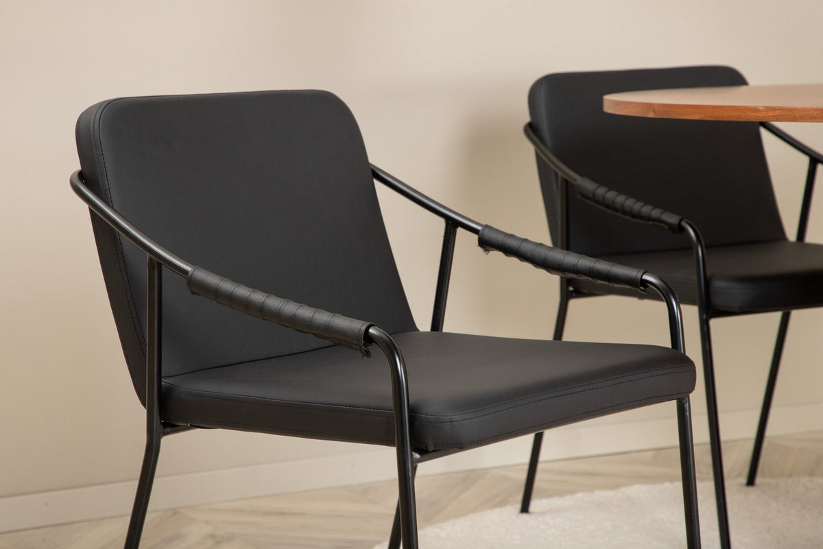 Rundes Esszimmerset mit Tisch aus MDF in Nussbaum-Optik ⌀110 cm und zwei schwarzen Stühlen mit Pulverbeschichtung und Eisenbeinen.