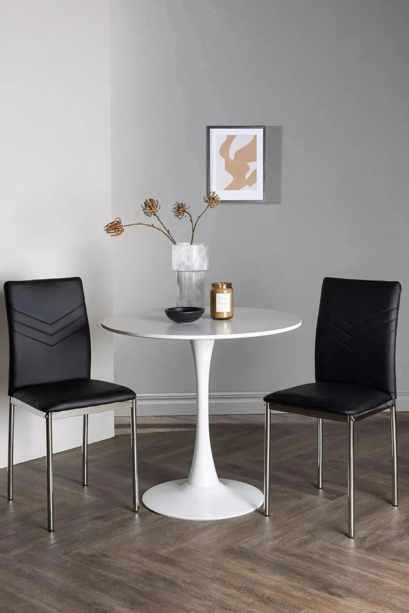 Elegantes Esszimmerset: Weißer MDF-Tisch mit Stahlfuß, schwarze Kunstlederstühle, ideal für kleine Räume.