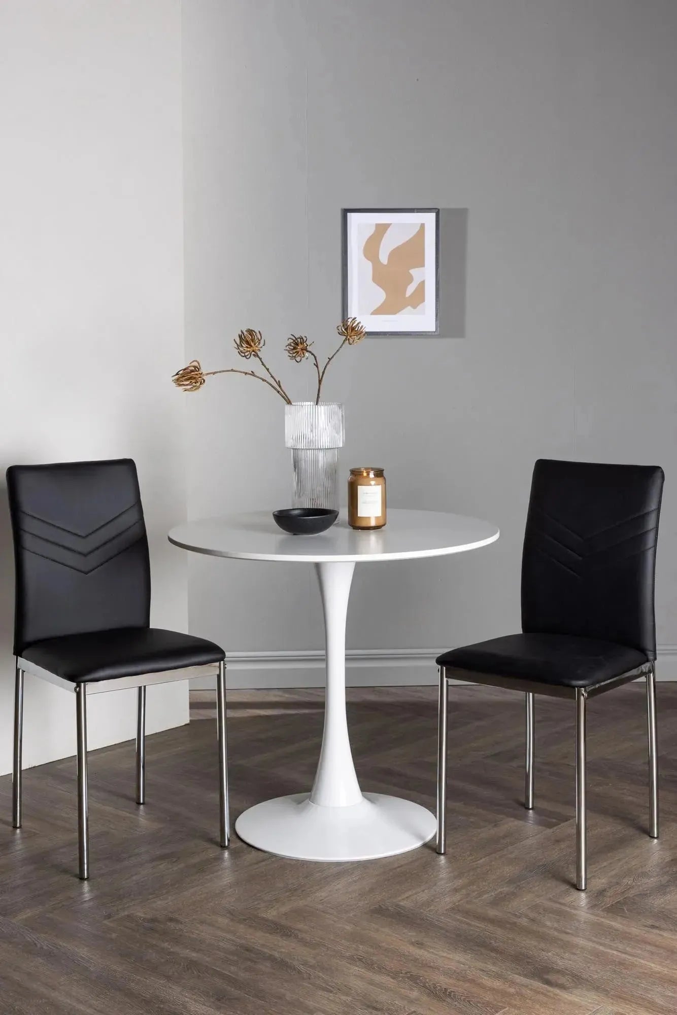 Elegantes Esszimmerset: Weißer MDF-Tisch mit Stahlfuß, schwarze Kunstlederstühle, ideal für kleine Räume.