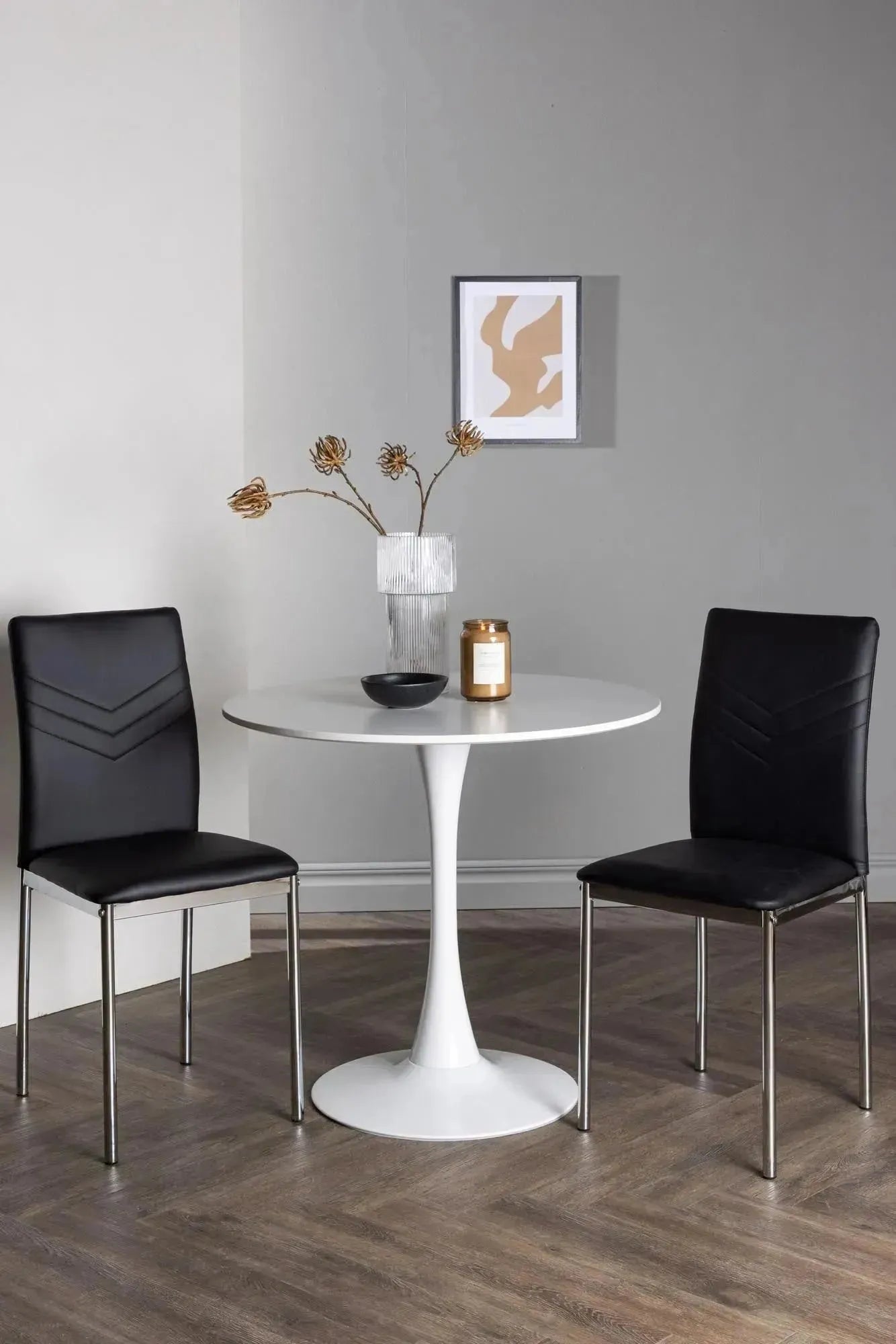 Elegantes Esszimmerset: Weißer MDF-Tisch mit Stahlfuß, schwarze Kunstlederstühle, ideal für kleine Räume.