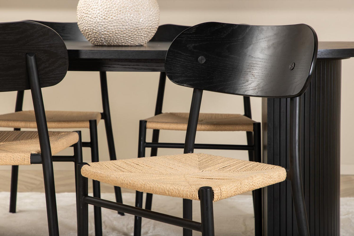 Rundes Esszimmerset Bianca mit Stuhl Polly: Tisch aus MDF und Furnier in Walnuss, vier schwarze Stühle mit Metallbeinen und Seilsitzen.
