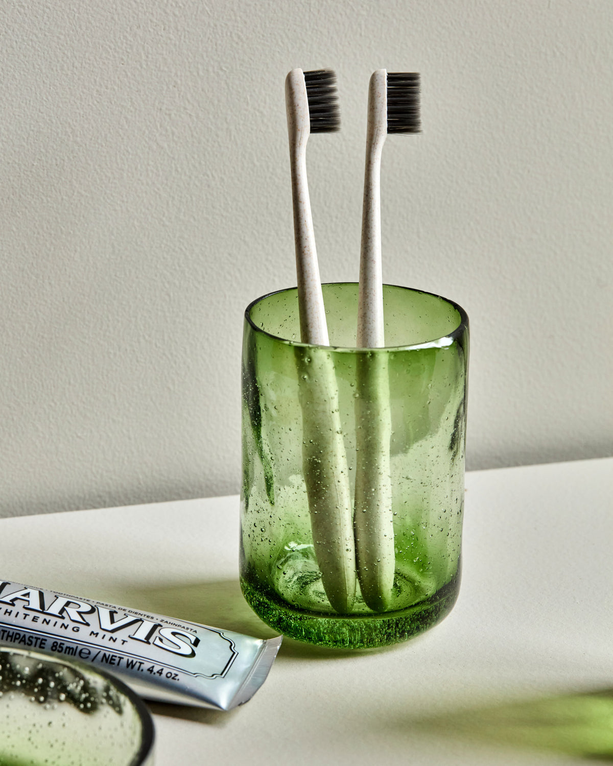 Grüner Zahnputzbecher HDWah aus Glas mit unebener Oberfläche und feinen Luftbläschen