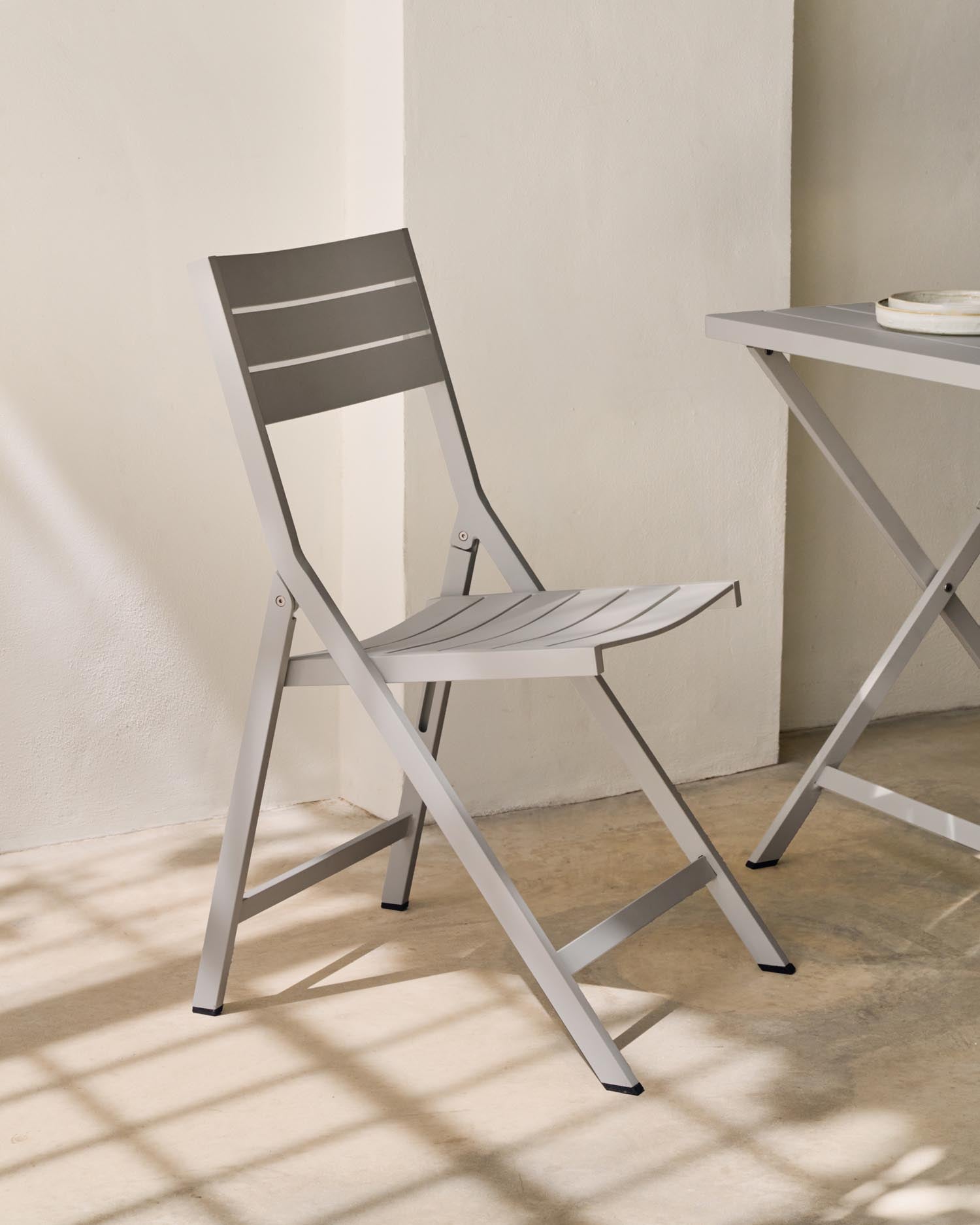 Stylischer, faltbarer Gartenstuhl Torreta von Kave Home aus Aluminium und Massivholz. Wetterfest, leicht und perfekt für jeden Außenbereich.