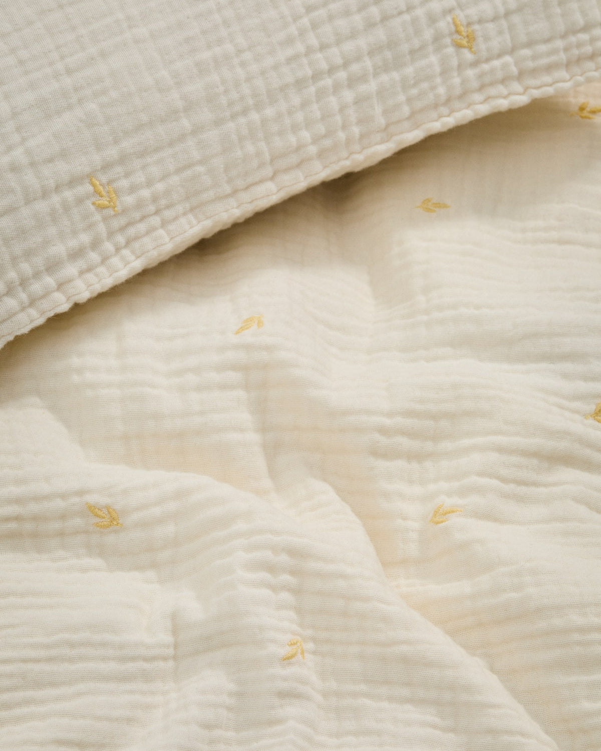 Bettbezug und Kopfkissen aus ecrufarbener Baumwoll-Doppelgaze mit aufgestickten Blättern, für Babybett, Set Dorani von Kave Home.