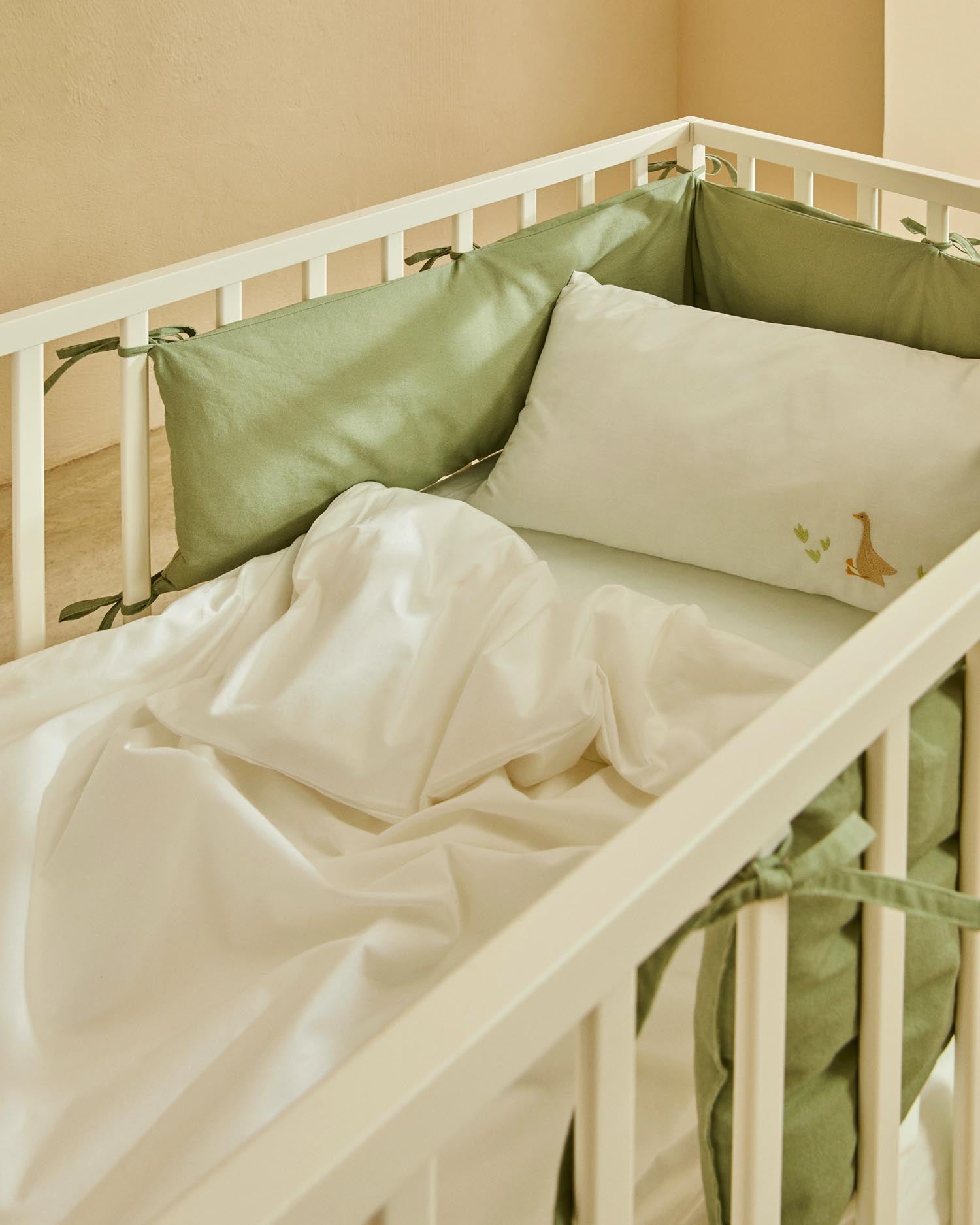 Elegantes Gitterbett aus massiver Buche mit weißem Finish, anpassbarer Matratzenhöhe, ideal für Babys und Kleinkinder.