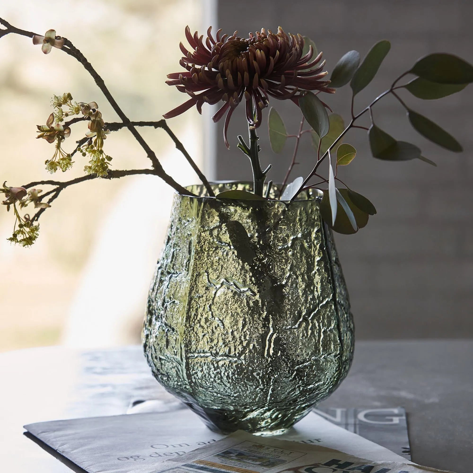 Die Moun Vase von House Doctor: Ein grünes Glas-Statement mit asymmetrischem Design und Luftbläschen, ideal für Blumen.