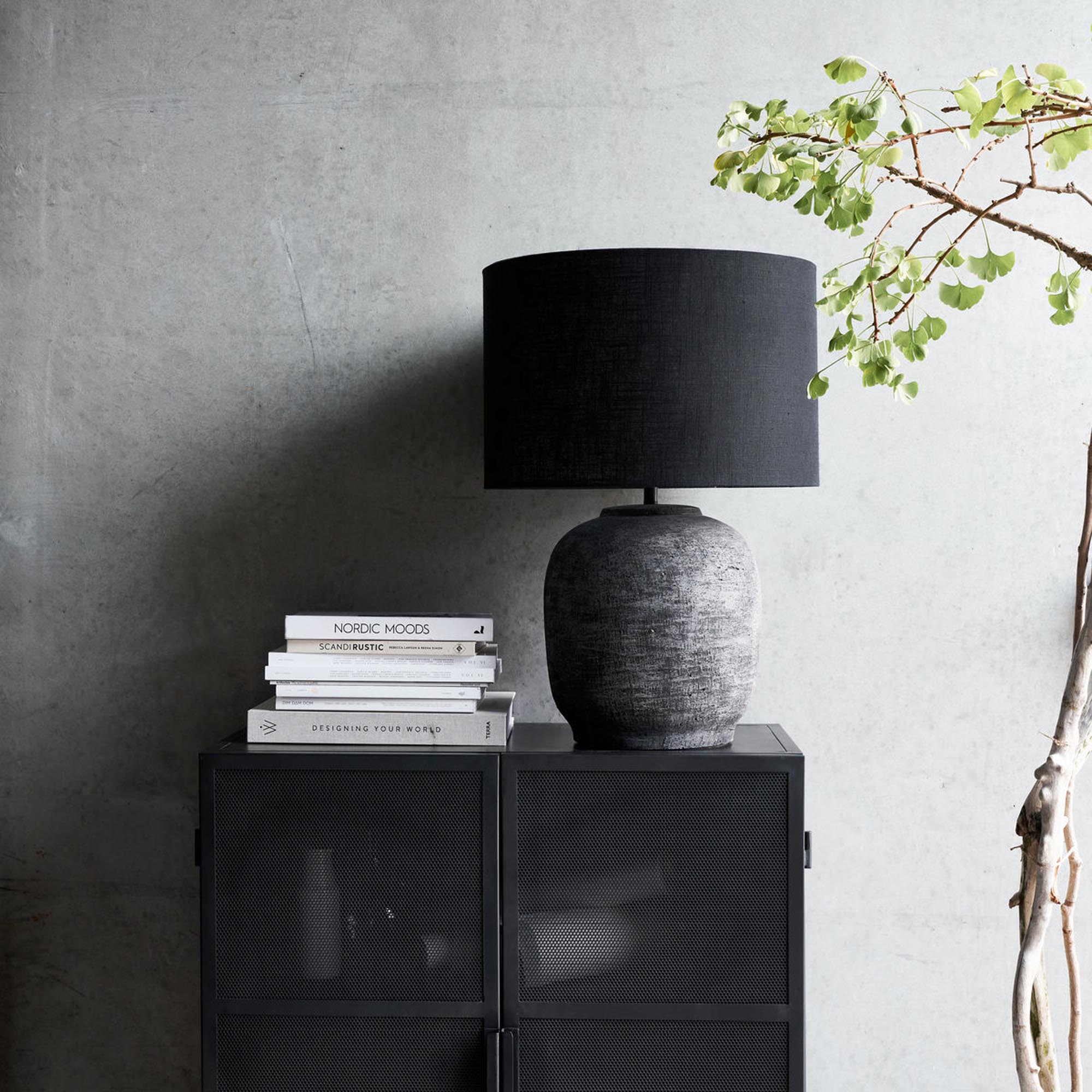 Die Tahi Tischlampe von House Doctor: Eleganter Lehmfuss, schwarzer Stoffschirm, ideal für Beistelltische und Nachttische.