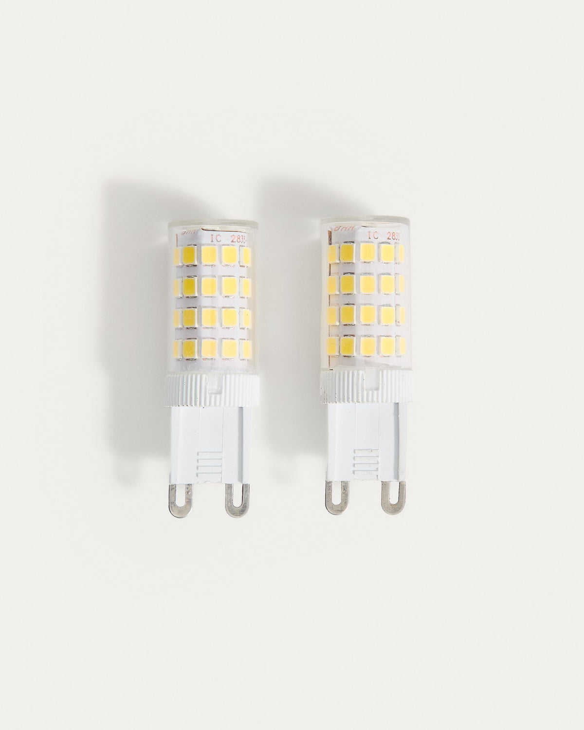 Zwei transparente LED-Lampen G9 von Kave Home mit rundem, kompaktem Sockel und schmaler Form auf weissem Hintergrund abgebildet.