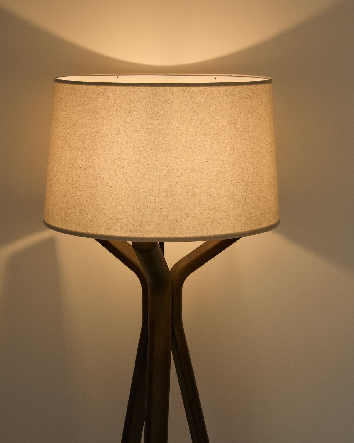 Stehlampe Ubira aus Eschenholz mit dunklem Finish, stativförmiger Basis und Lampenschirm aus Leinen in Braun.