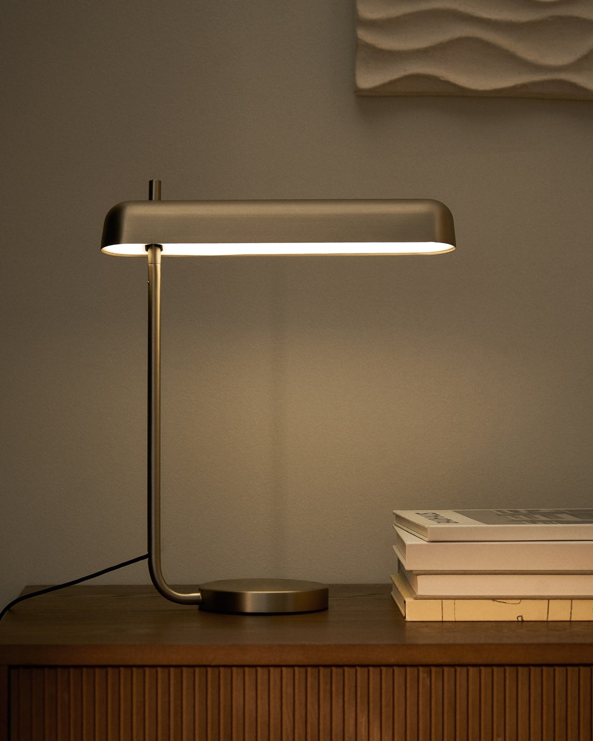 Graue Tischlampe Nelaia aus Stahl mit Kippschalter, Sockel aus Metall, schlanke zylindrische Form, LED-Leuchtmittel sichtbar.