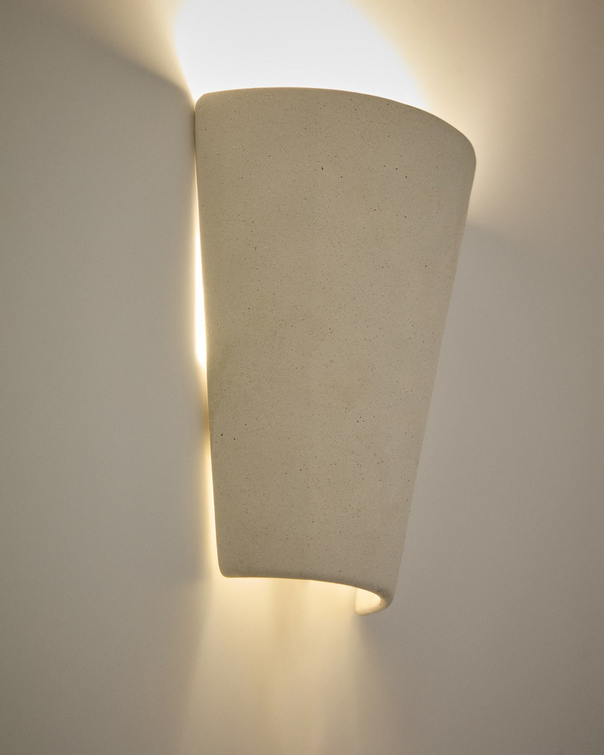 Wandleuchte Ceren aus weisser Keramik mit klaren, runden Formen, Masse 19x9.5x21 cm, montiert an einer hellen Innenwand.