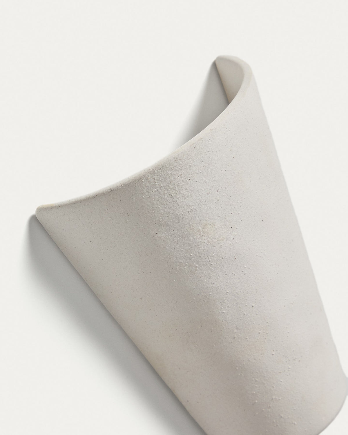 Wandleuchte Ceren aus weisser Keramik mit klaren Formen und runder Silhouette, montiert an einer hellen Wand, Grösse 12x6x14 cm.