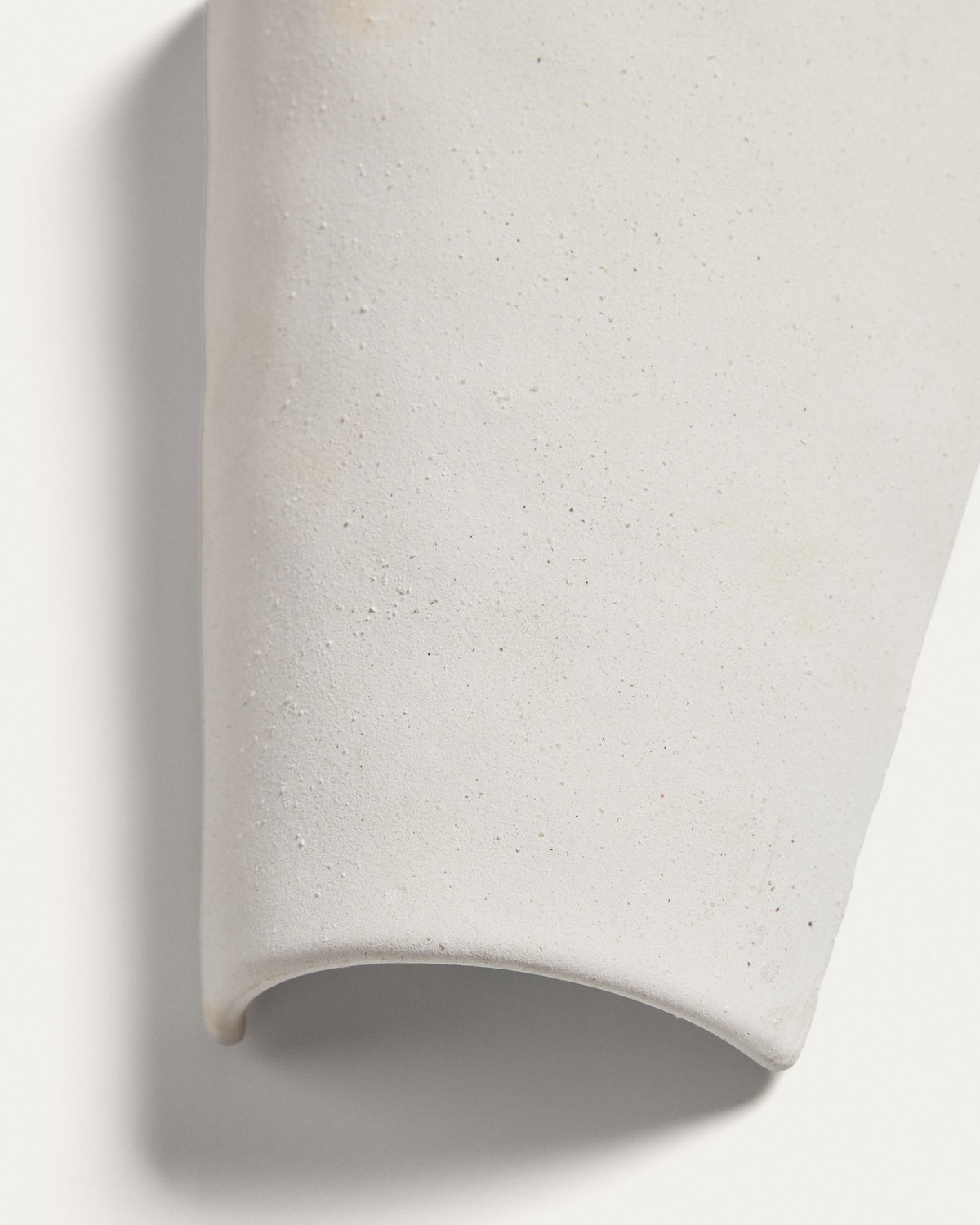 Wandleuchte Ceren aus weisser Keramik mit klaren Formen und runder Silhouette, montiert an einer hellen Wand, Grösse 12x6x14 cm.