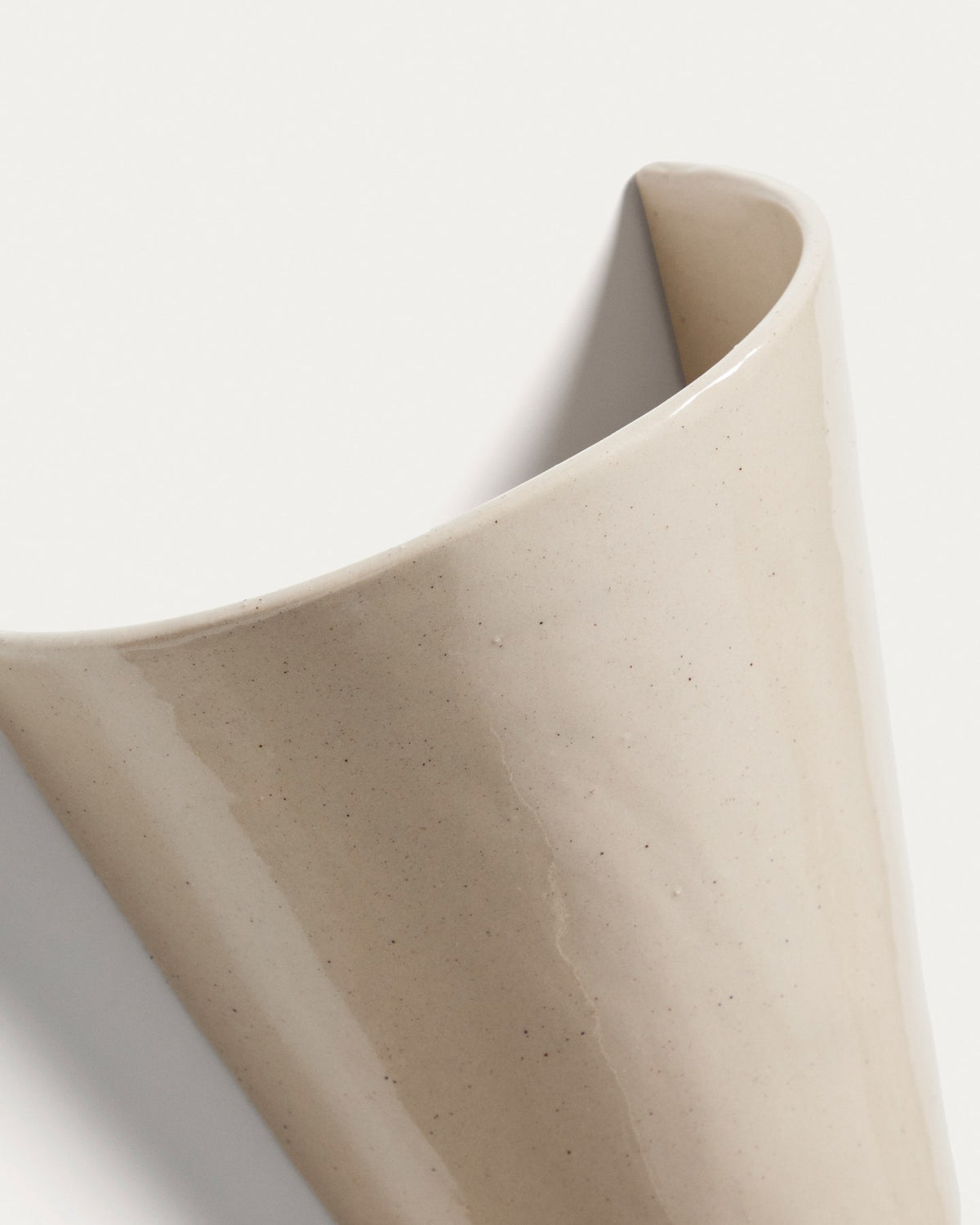 Beigefarbene Wandleuchte Ceren aus Keramik mit schlichter, runder Form, montiert an einer hellen Wand, Grösse 12 x 6 x 14 cm.