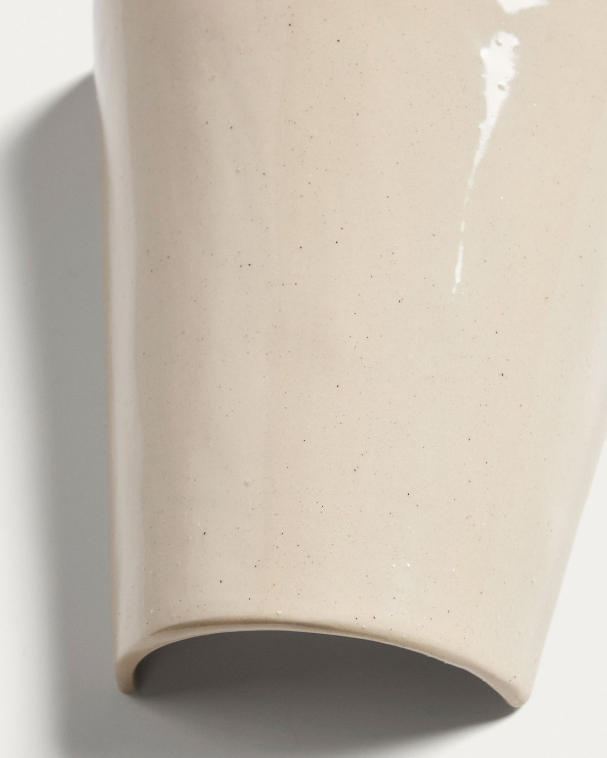 Beigefarbene Wandleuchte Ceren aus Keramik mit schlichter, runder Form, montiert an einer hellen Wand, Grösse 12 x 6 x 14 cm.