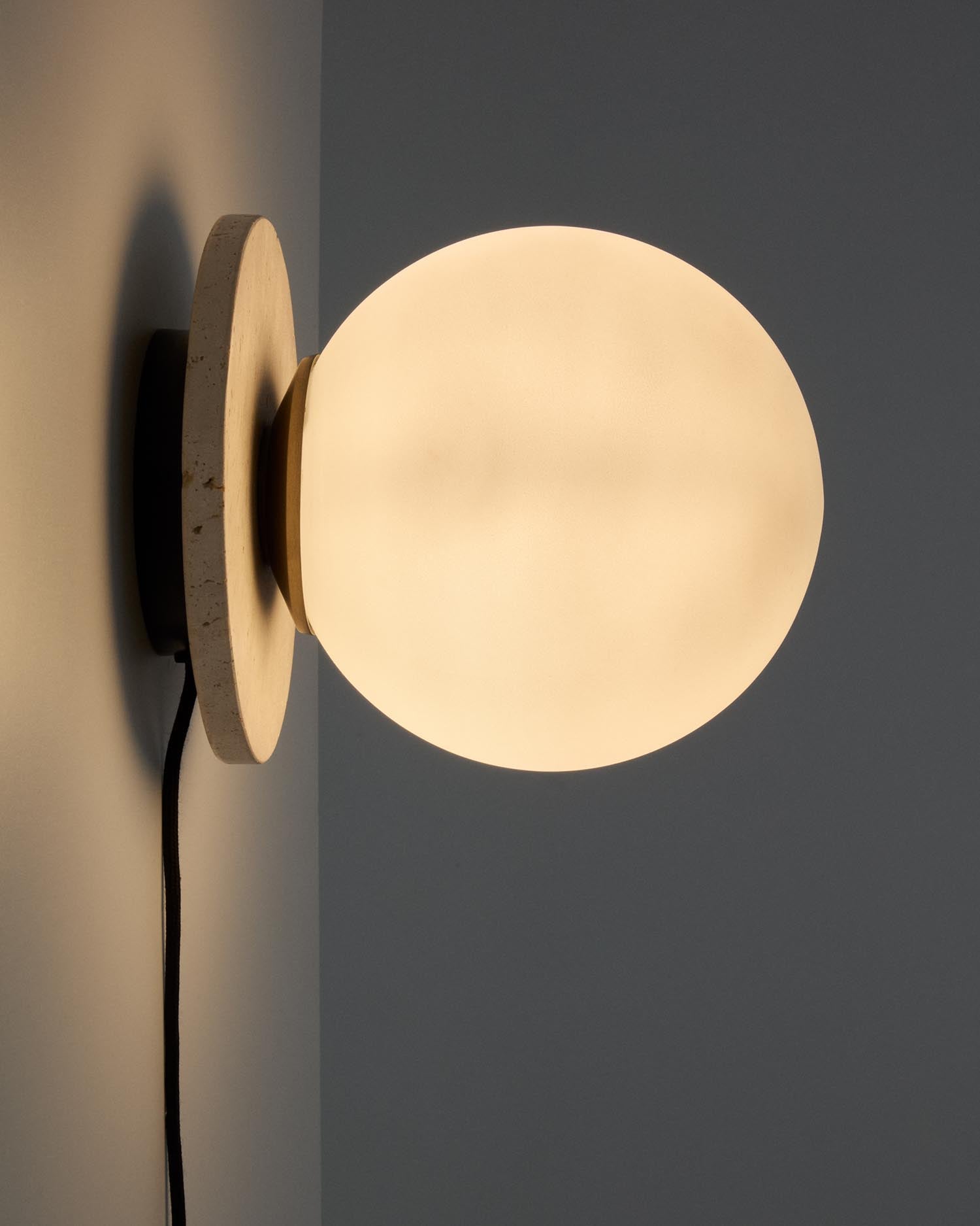 Elegante Wandleuchte Malachi aus Travertinstein und Glas, ergänzt durch Massivholzelemente für ein warmes, modernes Wohngefühl.